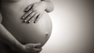 Expectant mother holding her belly with both hands in the third trimester