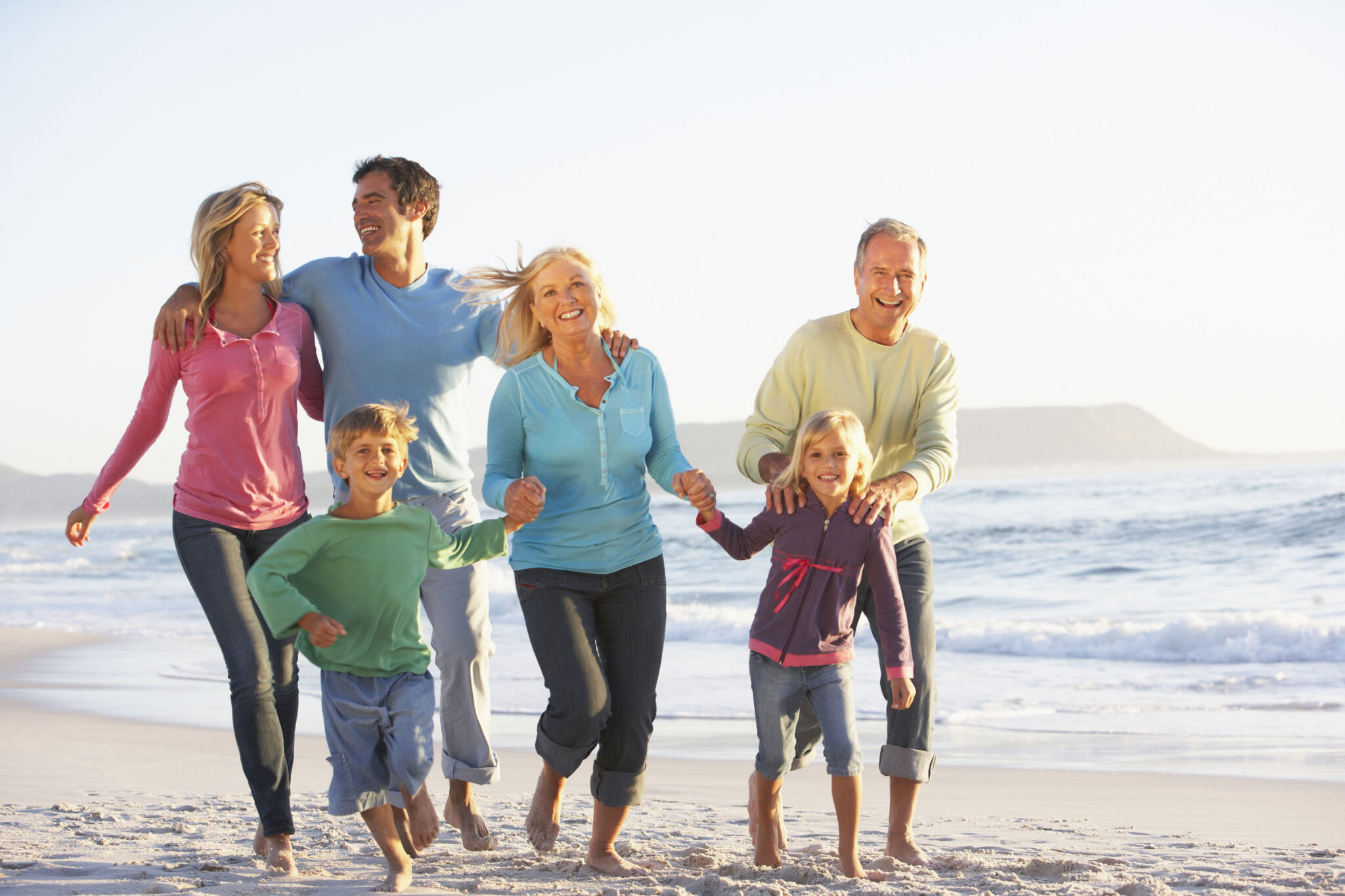 Three generations of one family walking barefoot along the beach together