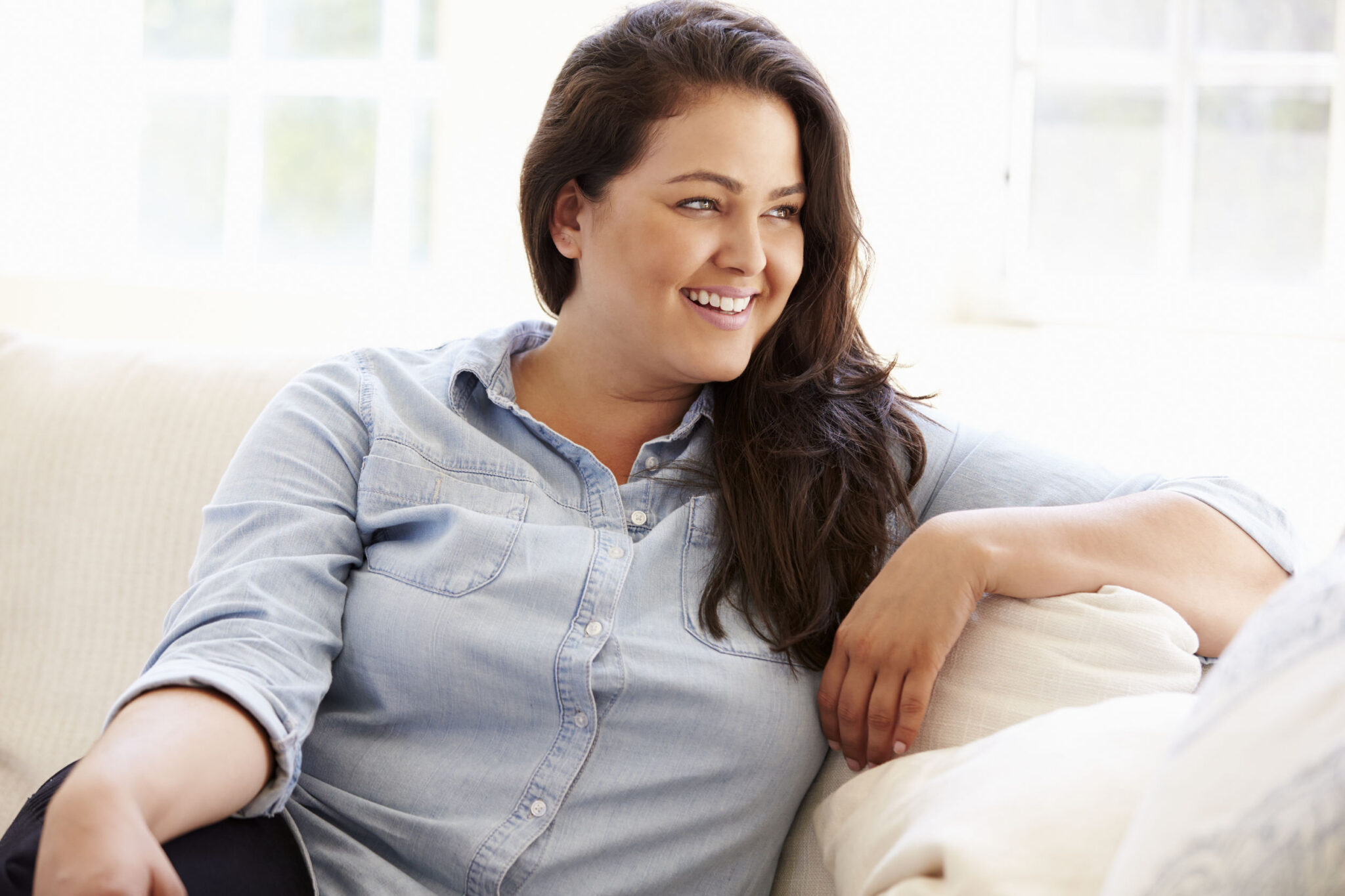 Smiling woman relaxing on a sofa at home