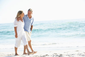Older couple walking arm in arm along the beach