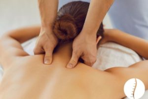 Massage therapist working along a client's upper back and shoulders