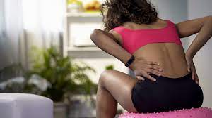 Woman in workout clothes holding her lower back in pain