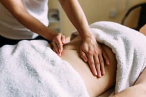 Therapist performing abdominal fertility massage on a draped client