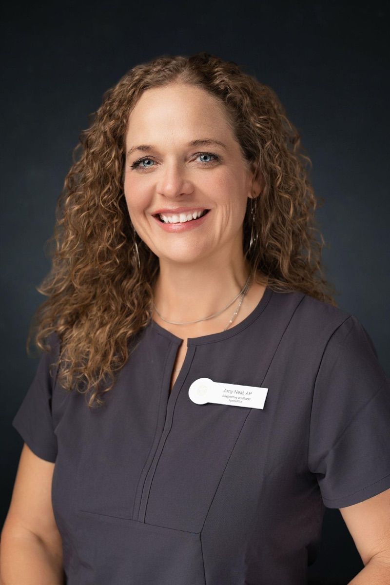 Amy Neal, Integrative Wellness Specialist at Health Pointe Jacksonville, smiling in a charcoal scrub top